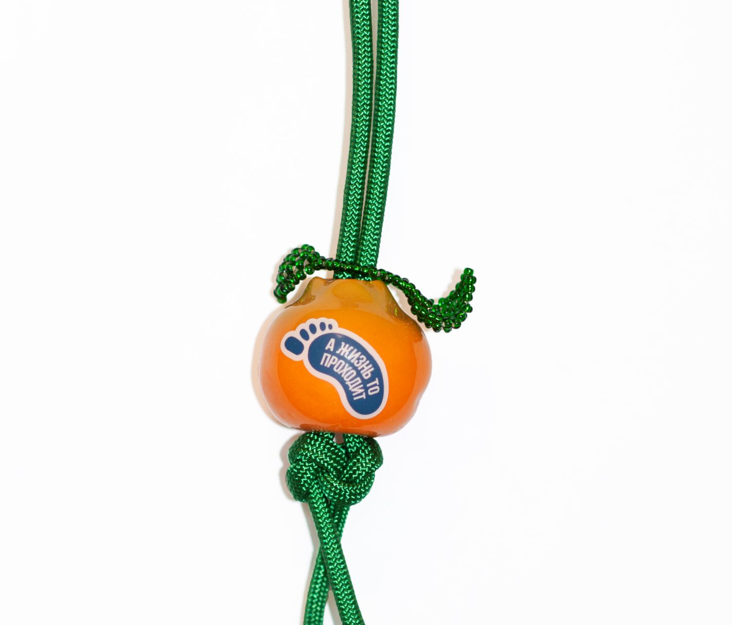 Брелок «Мандаринчик с наклейкой 1» Настасьи Красноперовой – фарфоровый оранжевый брелок с зелёным шнурком и надписью.