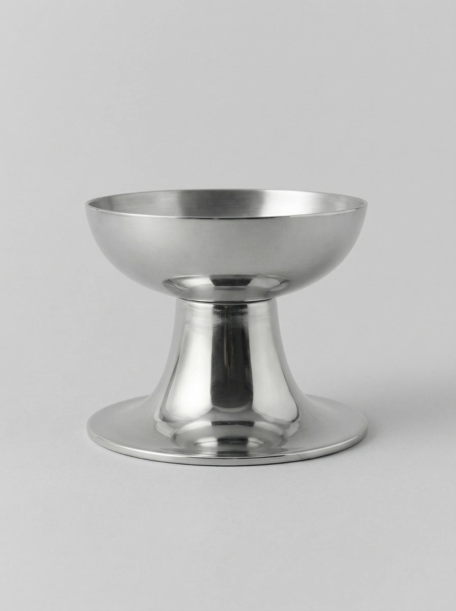 Креманка серебристого цвета с гладкой поверхностью и устойчивой ножкой в минималистичном стиле